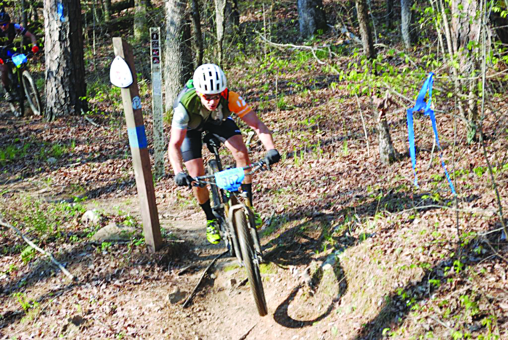 Some terrain along the Ouachita Challenge course is particularly challenging, or particularly exciting, according to riders. Shown here is an unidentified rider airborne as he comes off a sharp drop-off near Big Brushy Recreation Area.  The next challenge facing riders, at this point, is Blowout Mountain. Riding 60 miles over scenic, but rough, terrain has made the Ouachita Challenge a much sought after race. Photo by Derwood Brett