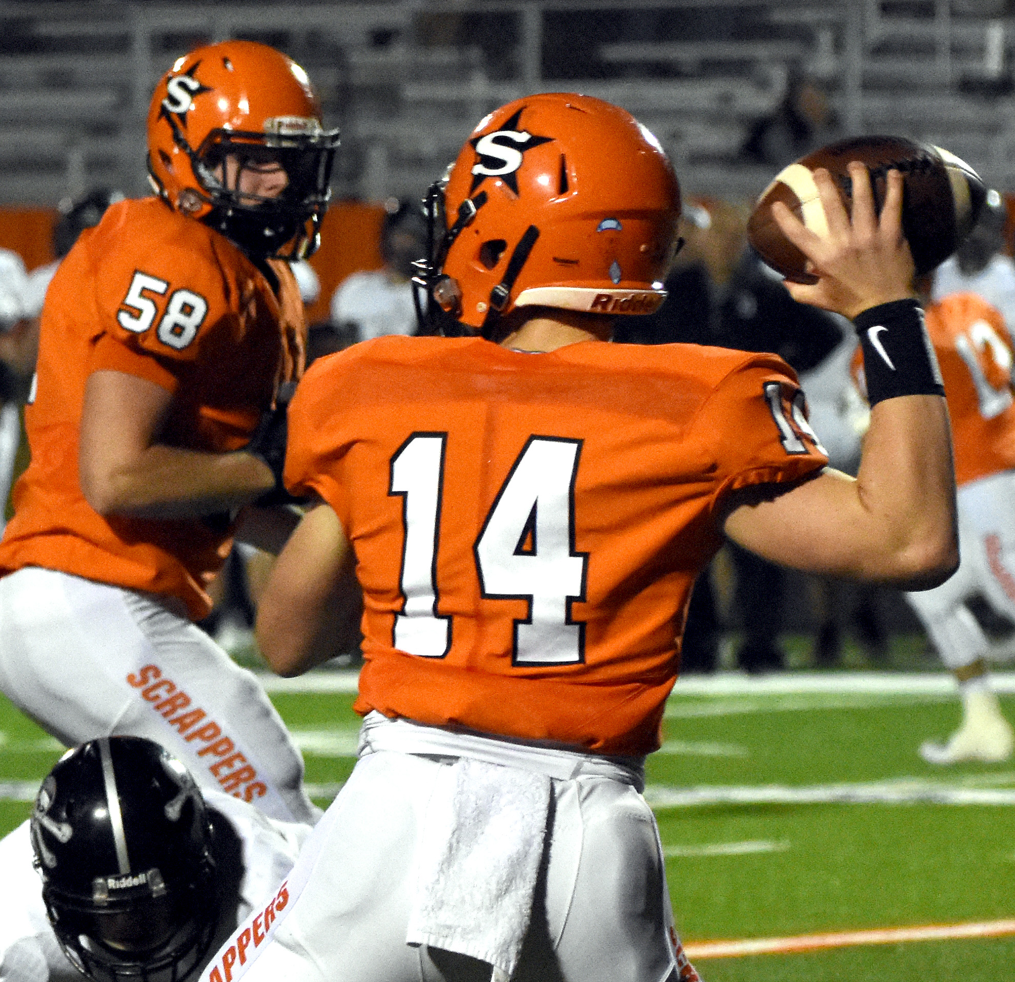 Tyler Hanson (14) gets set to pass as Triston Rhodes keeps Dover away.